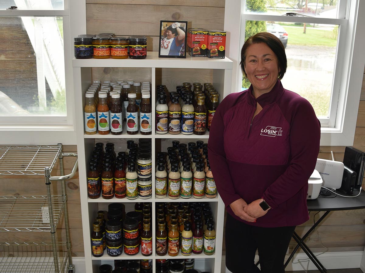 Sonya smiling for the camera next to shelves with products she has for sale